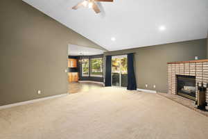 Unfurnished living room featuring high vaulted ceiling, ceiling fan, light colored carpet, and a fireplace