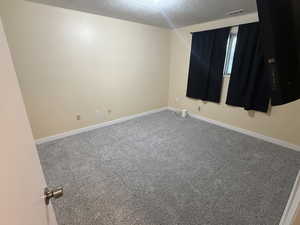 Unfurnished room with carpet and a textured ceiling