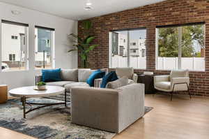 Living room with lofted ceiling, light hardwood / wood-style flooring, and brick wall