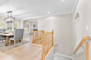 Dining space featuring wood-type flooring, a stone fireplace, and crown molding