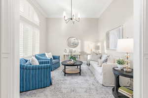 Living room with carpet, ornamental molding, and an inviting chandelier