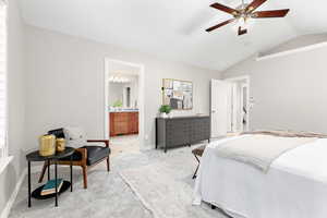 Carpeted bedroom featuring ceiling fan, connected bathroom, and vaulted ceiling