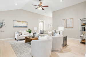 Living room featuring ceiling fan, light wood-type flooring, and vaulted ceiling