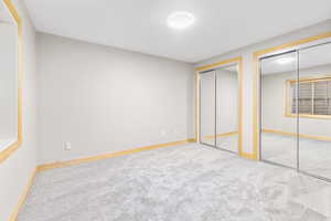 Unfurnished bedroom with multiple closets and light colored carpet