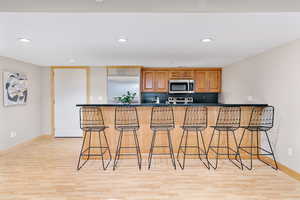 Kitchen featuring a breakfast bar, kitchen peninsula, appliances with stainless steel finishes, and light hardwood / wood-style flooring