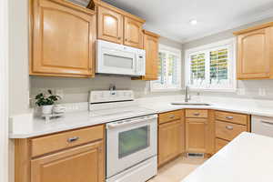 Kitchen with white appliances, ornamental molding, and sink