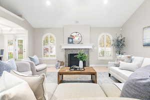 Living room with wood-type flooring, a tile fireplace, and vaulted ceiling