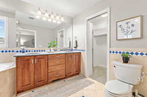 Bathroom with tile patterned floors, vanity, tile walls, and toilet