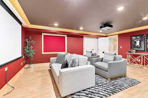 Home theater room featuring wood-type flooring and crown molding