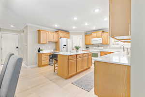 Kitchen with white appliances, sink, light wood-type flooring, a kitchen island, and a breakfast bar area