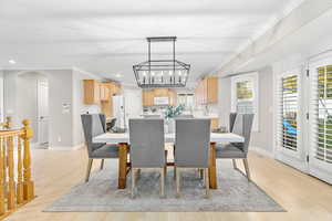 Dining space featuring a notable chandelier, plenty of natural light, light wood-type flooring, and crown molding