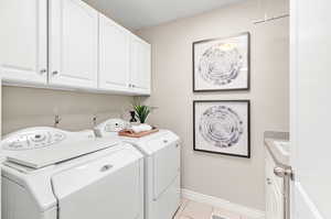 Washroom featuring cabinets, sink, washer and clothes dryer, and light tile patterned flooring