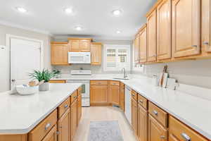 Kitchen with crown molding, sink, white appliances, and light wood-type flooring