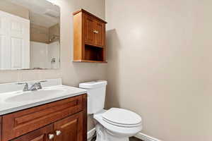 Bathroom featuring walk in shower, vanity, and toilet