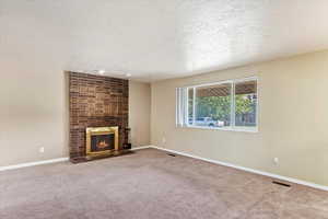 Unfurnished living room with carpet floors, a textured ceiling, and a fireplace