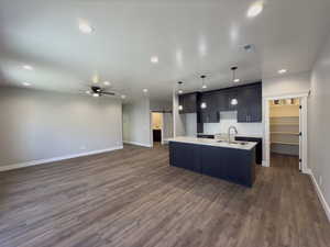 Kitchen featuring a barn door, dark hardwood / wood-style floors, pendant lighting, and a center island with sink