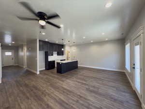 Unfurnished living room with ceiling fan, dark hardwood / wood-style flooring, and a healthy amount of sunlight