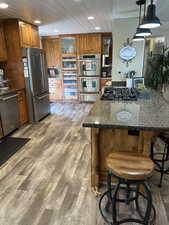 Kitchen featuring pendant lighting, wood ceiling, dark wood-type flooring, appliances with stainless steel finishes, and dark stone countertops