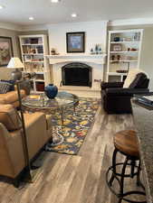 Living room with ornamental molding, hardwood / wood-style floors, a textured ceiling, and a fireplace