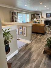 Interior space with ornamental molding, a textured ceiling, and dark hardwood / wood-style floors