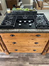 Details with dark stone countertops and black gas stovetop