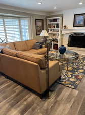 Living room with a brick fireplace, a textured ceiling, crown molding, and hardwood / wood-style floors