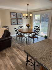 Dining room with a textured ceiling, ornamental molding, dark wood-type flooring, and a chandelier