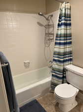 Bathroom featuring shower / tub combo, toilet, and tile patterned flooring