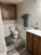 Bathroom with a textured ceiling, hardwood / wood-style flooring, vanity, and toilet