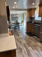 Kitchen with wood ceiling, sink, decorative light fixtures, dark wood-type flooring, and dishwasher