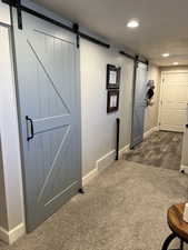 Hallway with a barn door and dark colored carpet