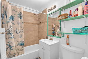 Full bathroom with vanity, shower / bath combo with shower curtain, and toilet