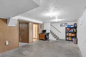 Basement featuring a textured ceiling and wood walls