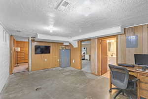 Office space featuring wooden walls and a textured ceiling