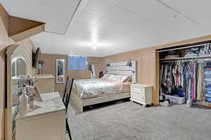 Bedroom featuring wooden walls, carpet floors, and a closet