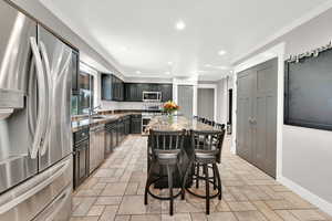 Kitchen featuring light stone counters, a center island, sink, a kitchen bar, and stainless steel appliances