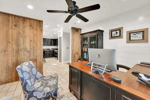 Office space with ceiling fan and wood walls