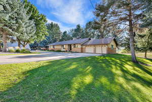 Ranch-style home featuring a garage and a front lawn