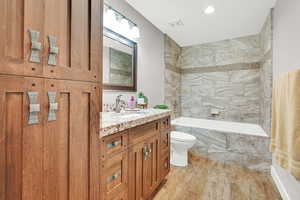 Full bathroom featuring tiled shower / bath combo, vanity, toilet, and hardwood / wood-style flooring