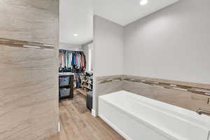 Bathroom with a bathtub, wood-type flooring, and tile walls