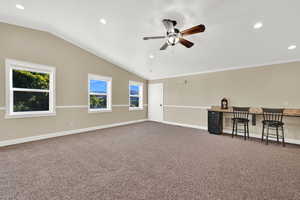 Carpeted empty room featuring built in desk, lofted ceiling, and ceiling fan