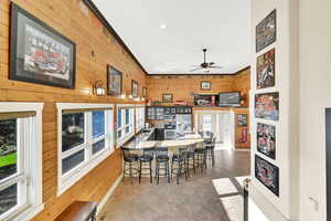 Dining space with ornamental molding, wooden walls, ceiling fan, and a wealth of natural light