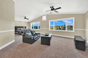 Carpeted living room with lofted ceiling, ceiling fan, and plenty of natural light