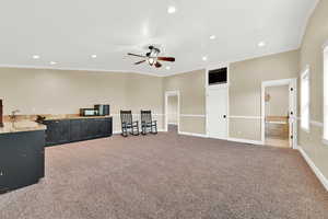 Interior space with ceiling fan, carpet floors, and crown molding