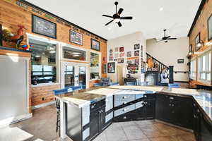 Kitchen featuring ceiling fan, light tile patterned flooring, wooden walls, and a breakfast bar