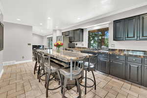 Kitchen featuring dark stone countertops, a center island, a breakfast bar area, and sink