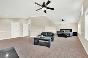 Living room with ornamental molding, carpet flooring, vaulted ceiling, and ceiling fan