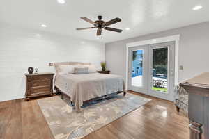 Bedroom featuring light hardwood / wood-style floors, a textured ceiling, wood walls, access to outside, and ceiling fan