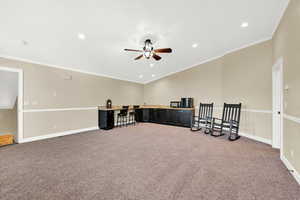 Empty room with ceiling fan, carpet floors, and crown molding