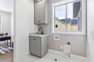 Clothes washing area featuring cabinets, electric dryer hookup, sink, and washer hookup